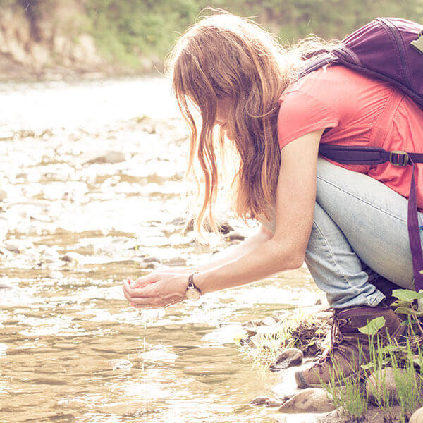wider view of girl scooping water from river